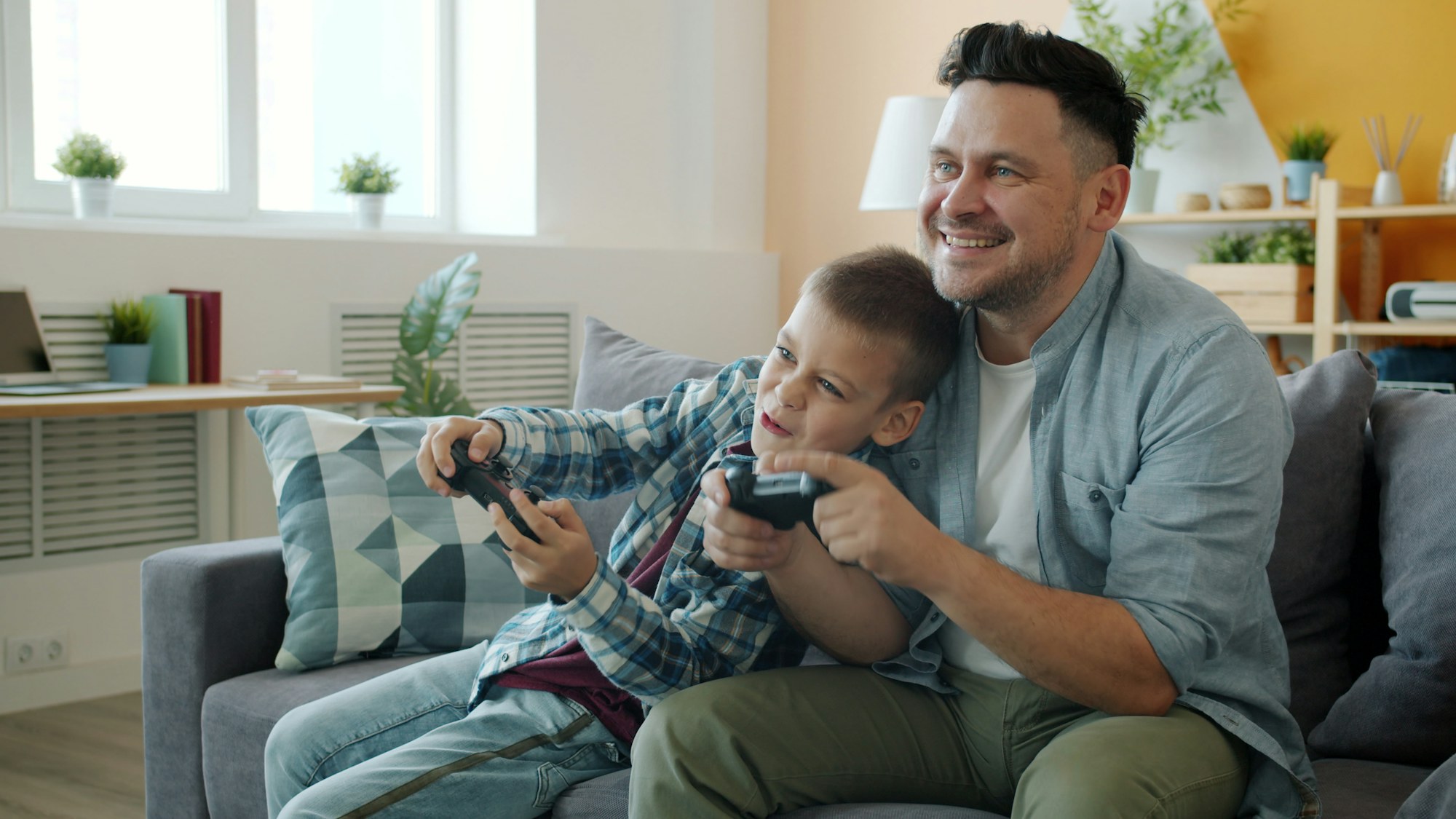A father and son playing a game together on the couch