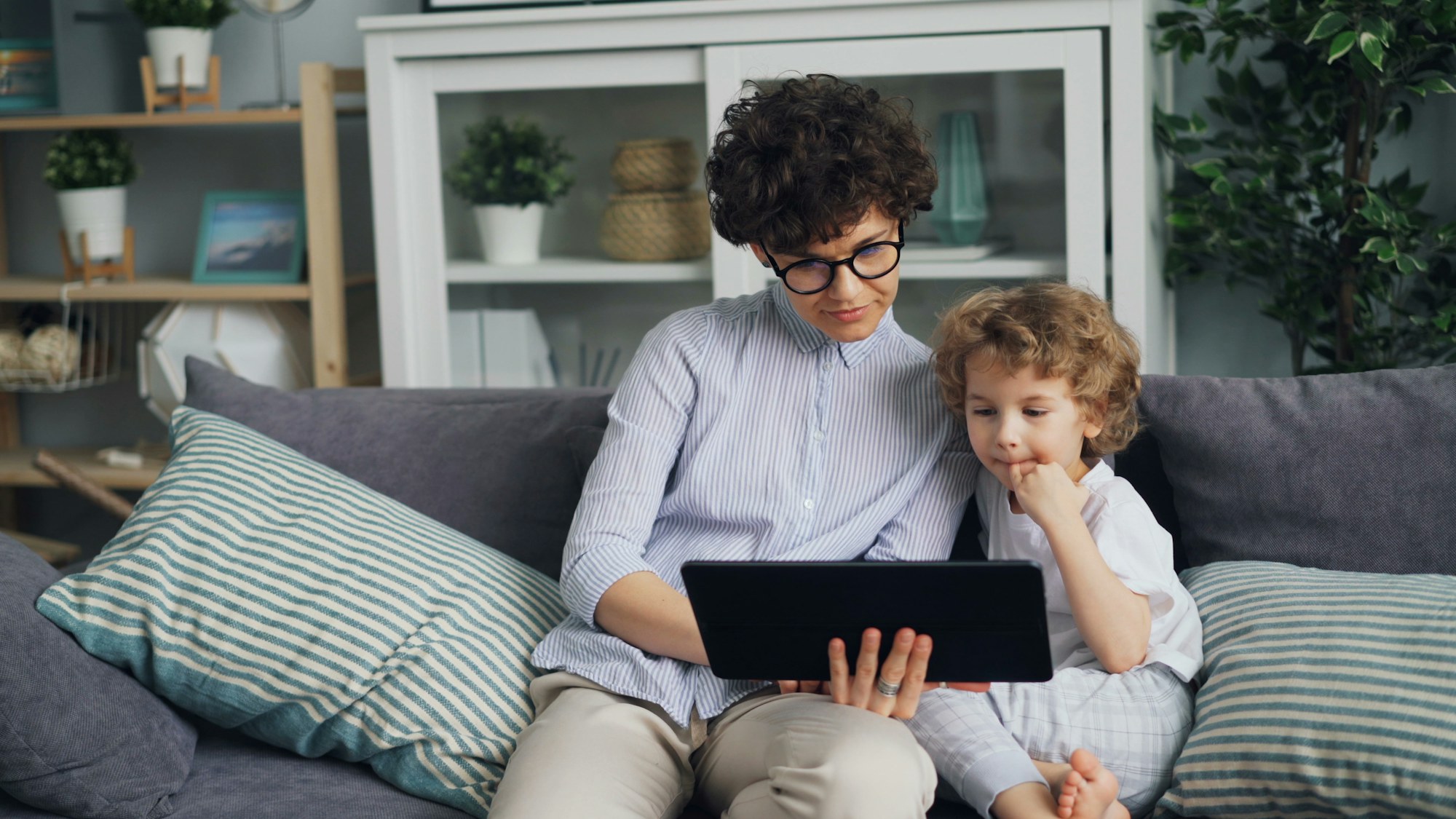 A parent and child on a couch looking at a tablet together