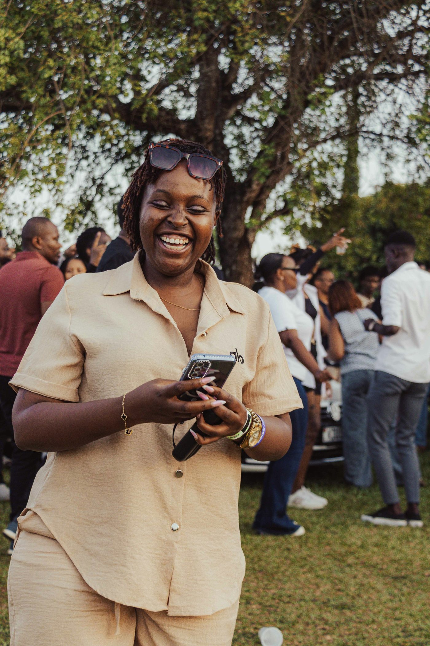 A woman laughing at her phone outdoors