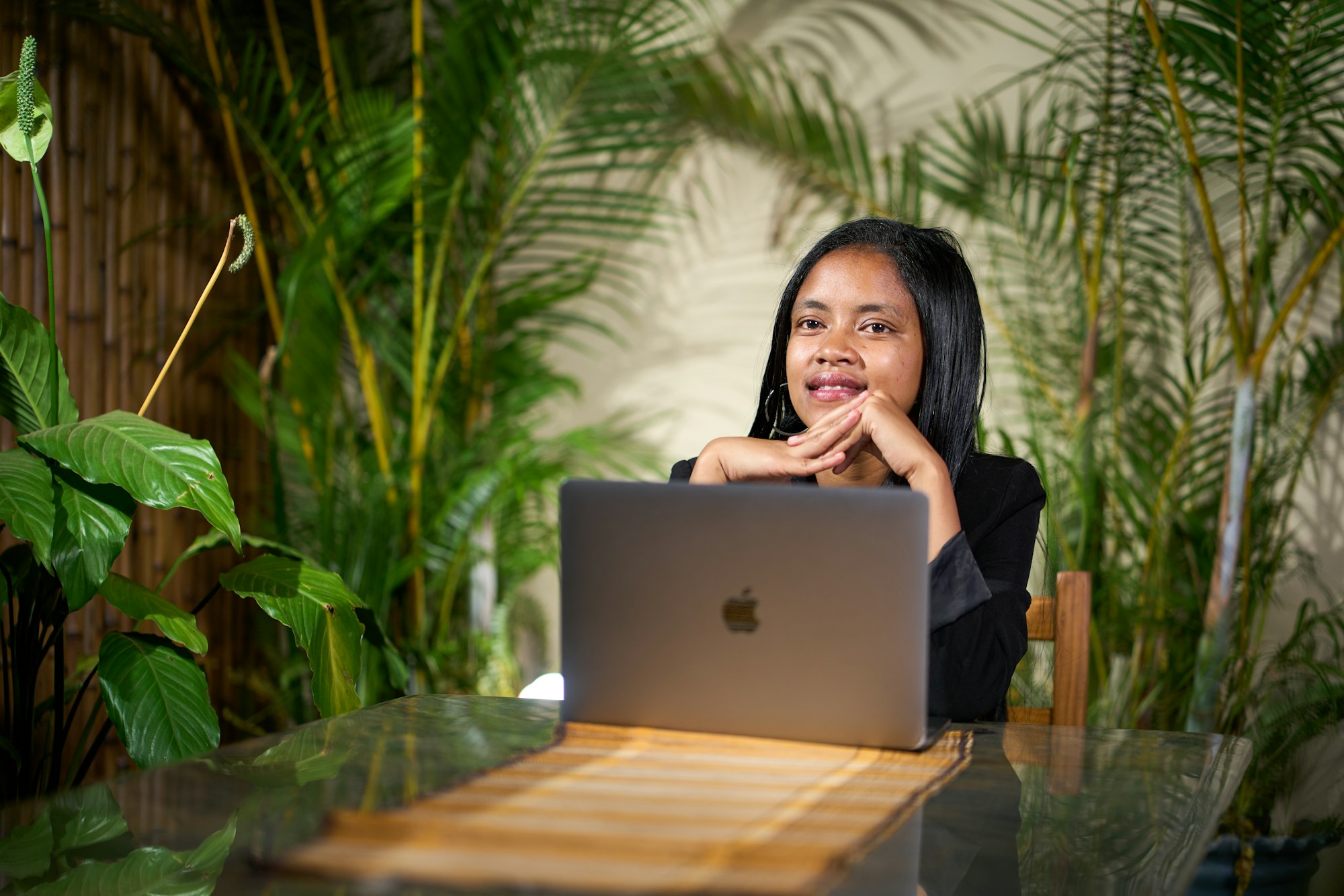 A designer at a laptop in a plant-filled studio
