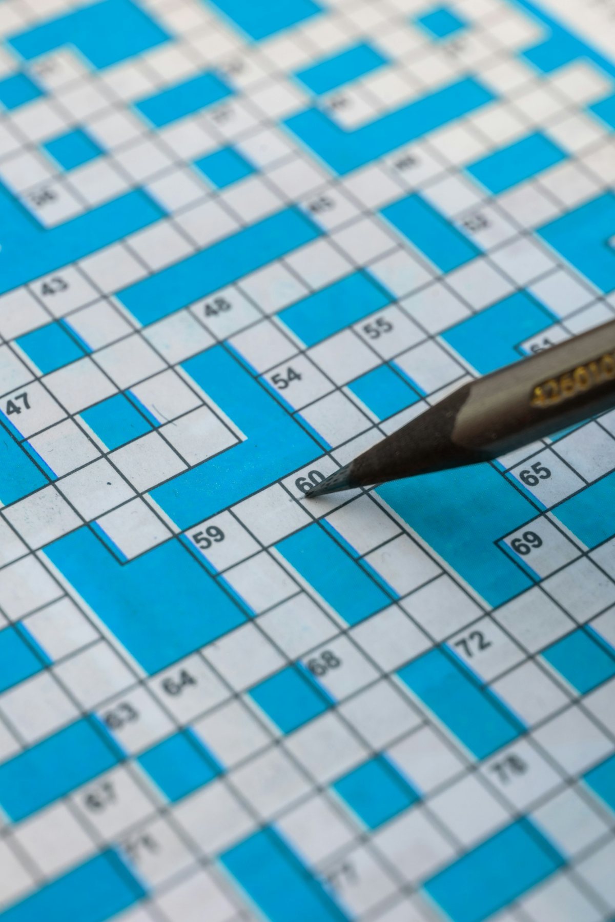 A pencil resting on a bright blue crossword grid